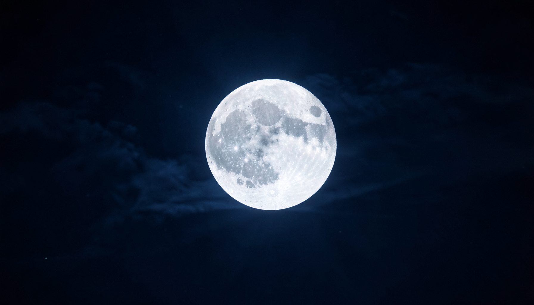 A glowing full moon in a dark night sky with subtle cloud wisps, deep navy and silver tones, evoking mystery and astrology
