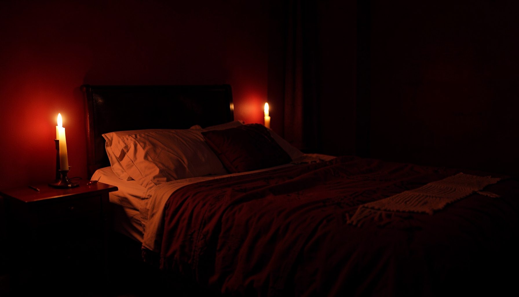 A dimly lit bedroom with soft candlelight, deep red and warm amber tones